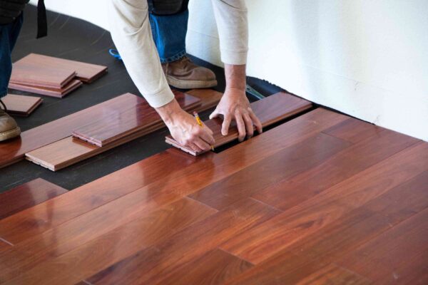 Man kneeling while installing vinyl flooring in a room